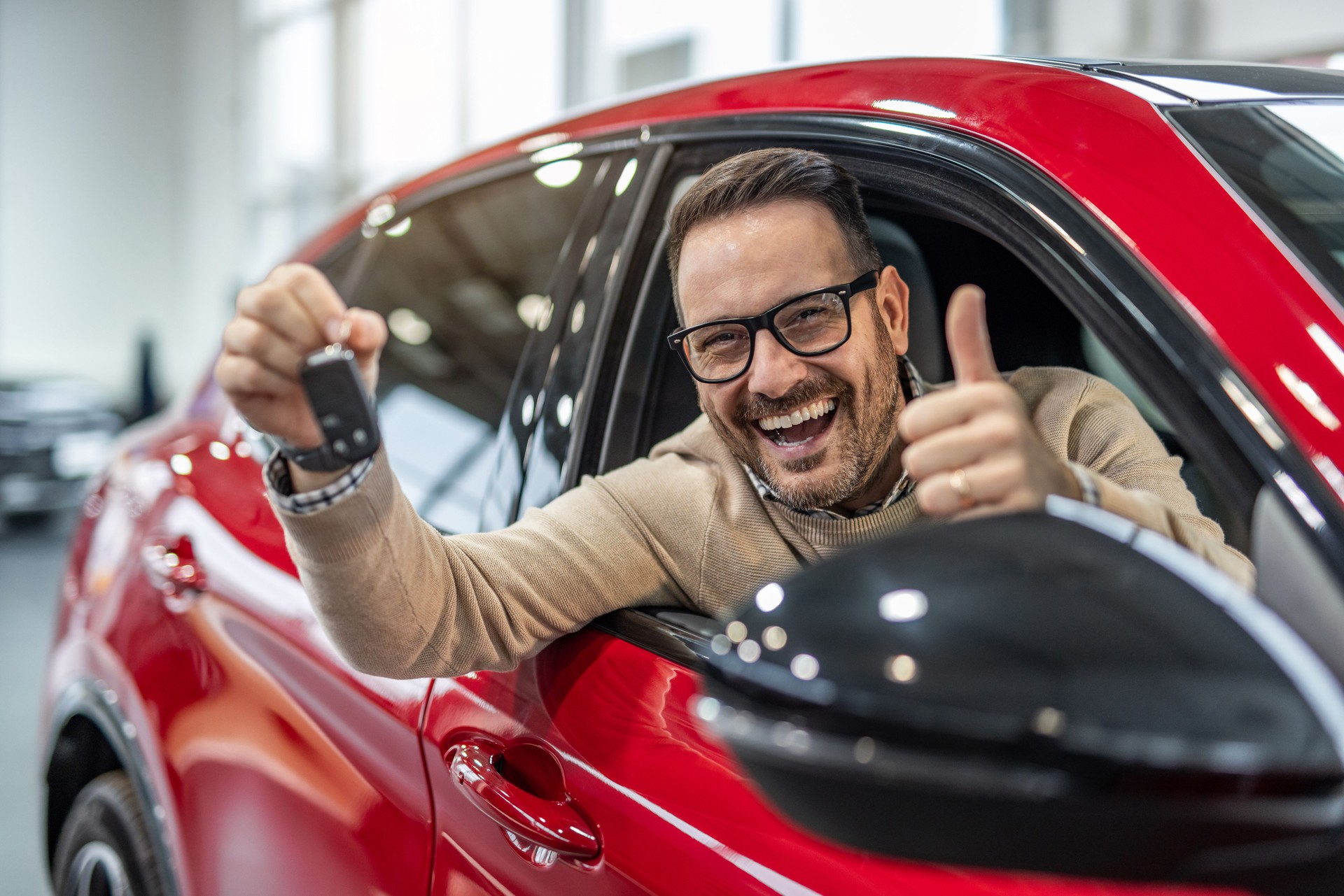 Happy man with keys to his new red car